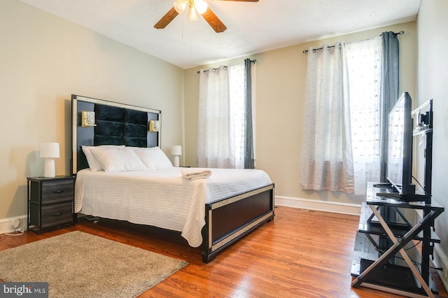 bedroom featuring ceiling fan, wood-type flooring, and multiple windows