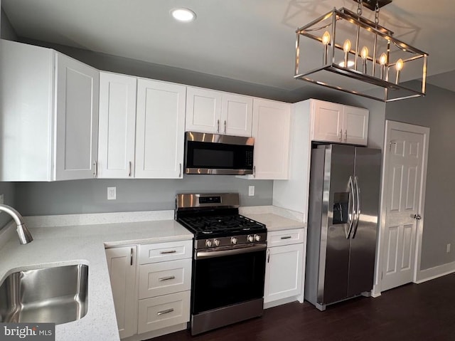 kitchen with white cabinets, stainless steel appliances, hanging light fixtures, and sink