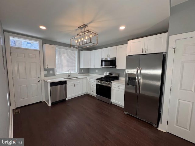 kitchen featuring pendant lighting, sink, dark hardwood / wood-style floors, appliances with stainless steel finishes, and white cabinetry