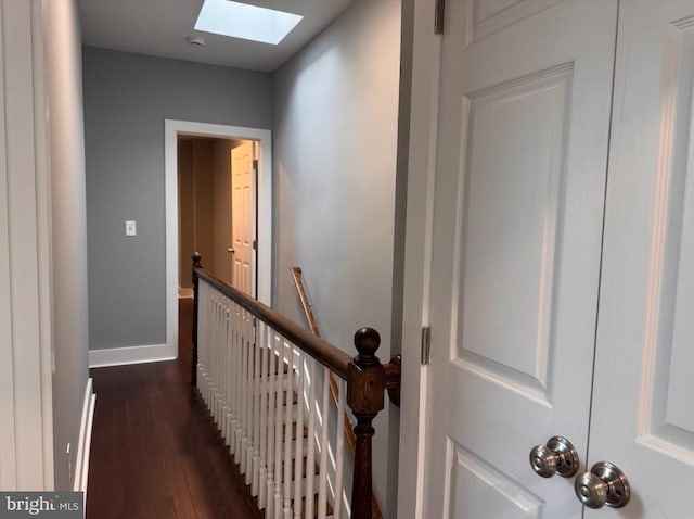 hall with dark wood-type flooring and a skylight