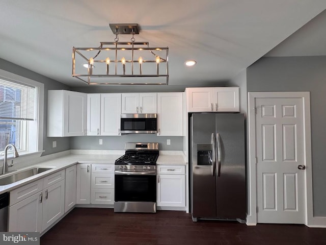 kitchen with stainless steel appliances, sink, pendant lighting, dark hardwood / wood-style floors, and white cabinetry