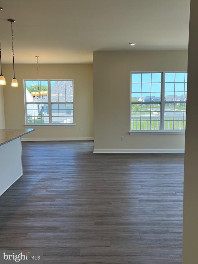 unfurnished living room with a notable chandelier and dark hardwood / wood-style floors