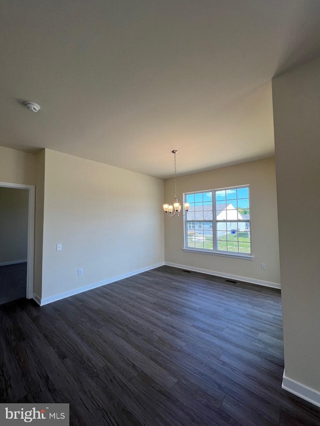 unfurnished room with dark hardwood / wood-style floors and an inviting chandelier