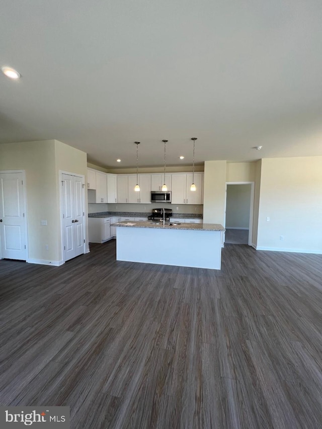 kitchen featuring white cabinetry, dark hardwood / wood-style floors, pendant lighting, a center island with sink, and appliances with stainless steel finishes