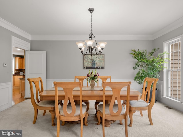 carpeted dining room featuring crown molding and an inviting chandelier