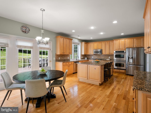 kitchen featuring pendant lighting, a center island, light wood-type flooring, and appliances with stainless steel finishes