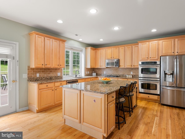 kitchen featuring light stone countertops, a wealth of natural light, a kitchen island, and stainless steel appliances