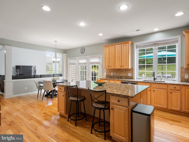 kitchen with a center island, light stone counters, light hardwood / wood-style floors, and sink