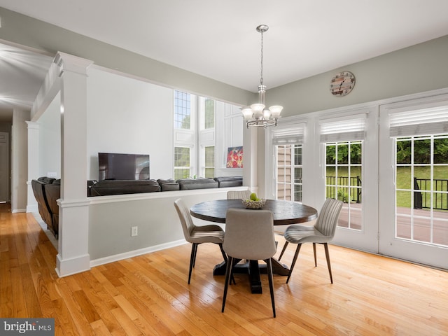 dining space with light wood-type flooring, an inviting chandelier, a healthy amount of sunlight, and ornate columns