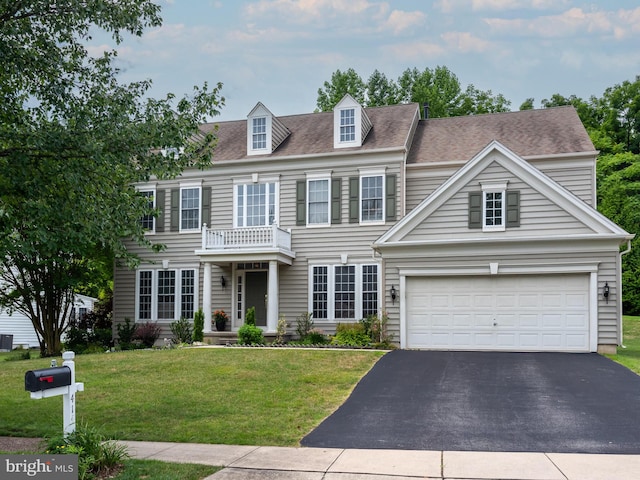 view of front of property with a balcony, a front yard, and a garage