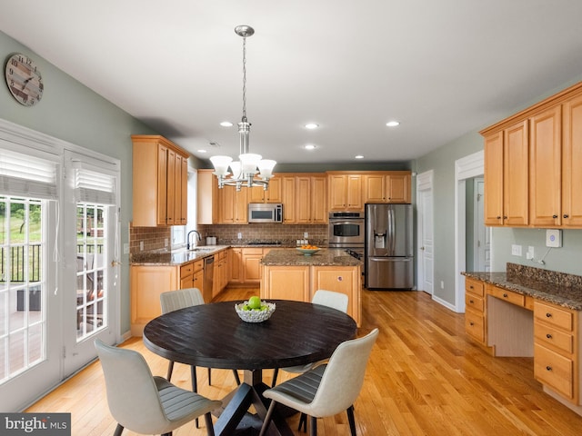 kitchen with dark stone countertops, light hardwood / wood-style flooring, a kitchen island, and stainless steel appliances