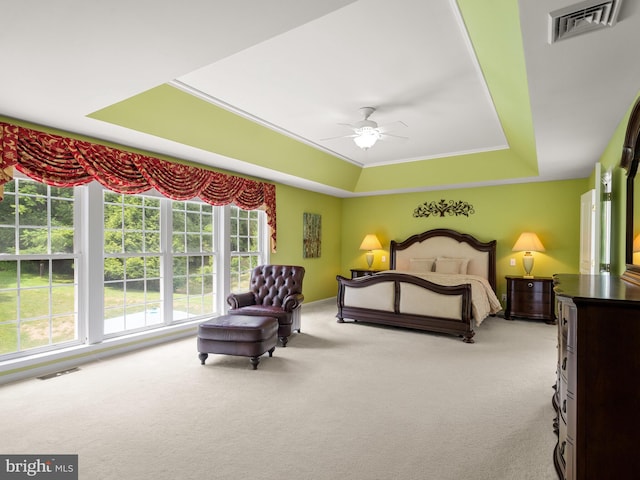 bedroom with a raised ceiling, ceiling fan, and light colored carpet