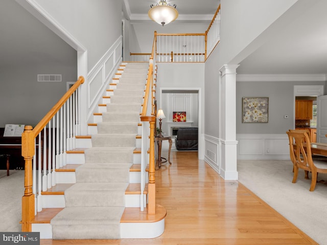 stairway with carpet, ornamental molding, a high ceiling, and ornate columns