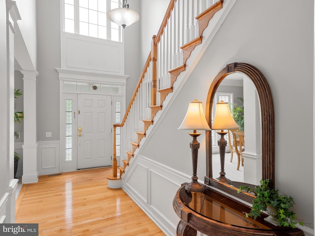 entrance foyer featuring a high ceiling, light wood-type flooring, and ornate columns