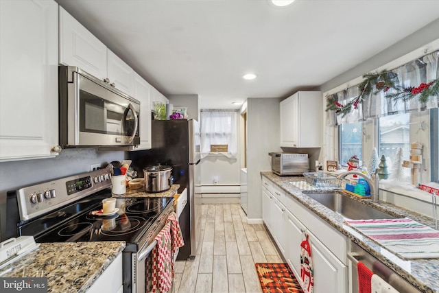 kitchen with light stone countertops, light wood-type flooring, stainless steel appliances, sink, and white cabinets