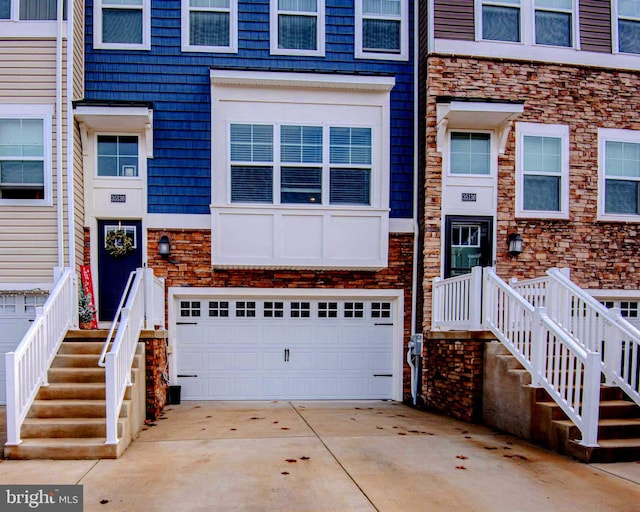 doorway to property with driveway, stone siding, and a garage