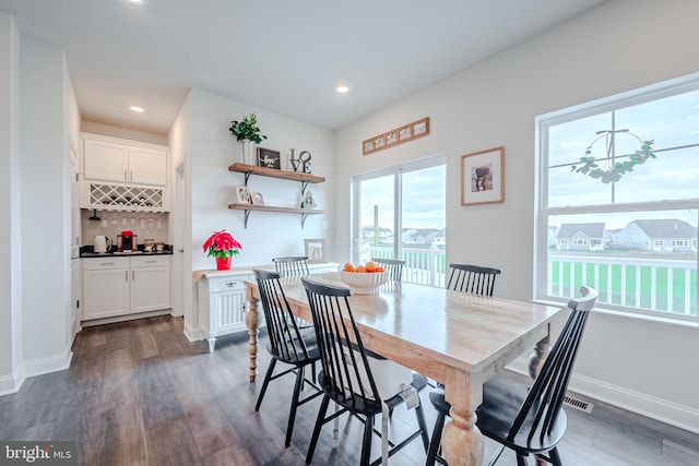 dining area with indoor bar and dark hardwood / wood-style floors