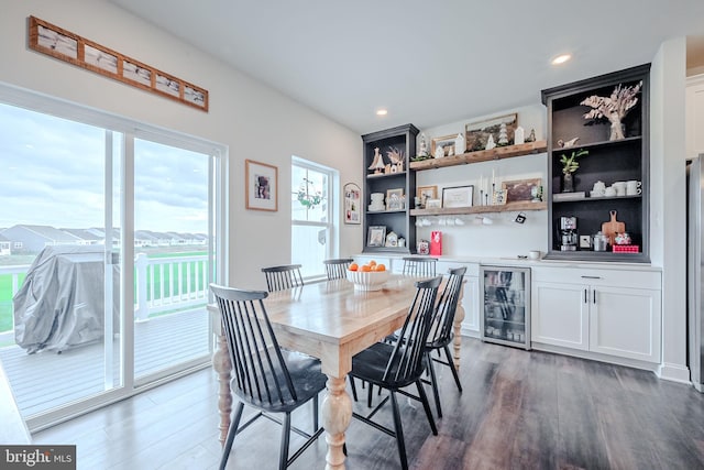 dining area featuring indoor bar, dark hardwood / wood-style floors, and wine cooler