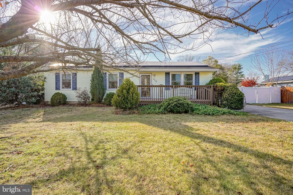 single story home featuring solar panels and a front lawn