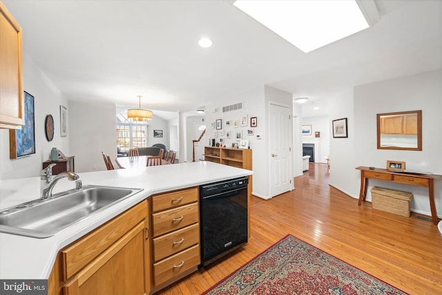 kitchen featuring dishwasher, ornate columns, sink, light hardwood / wood-style flooring, and decorative light fixtures