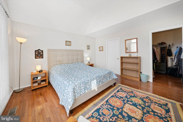 bedroom featuring a walk in closet, a closet, and hardwood / wood-style floors