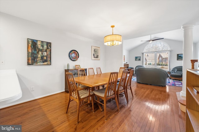 dining room featuring wood-type flooring, ceiling fan, vaulted ceiling, and decorative columns