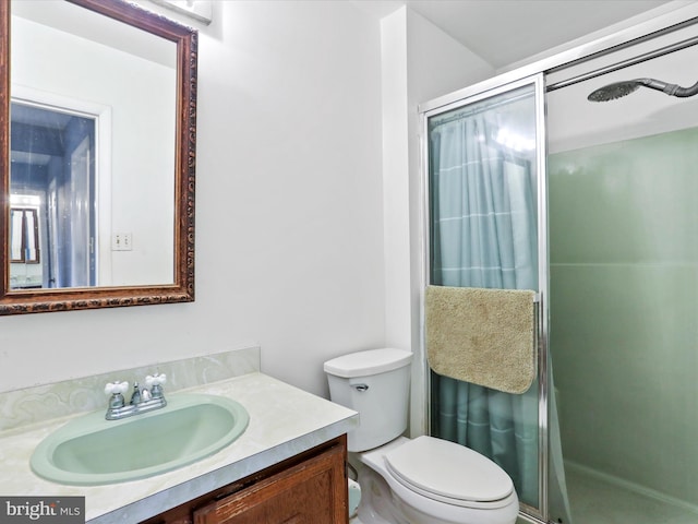 bathroom with vanity, toilet, and a shower with door