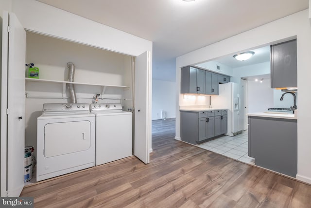 clothes washing area featuring washer and dryer, sink, and light hardwood / wood-style flooring