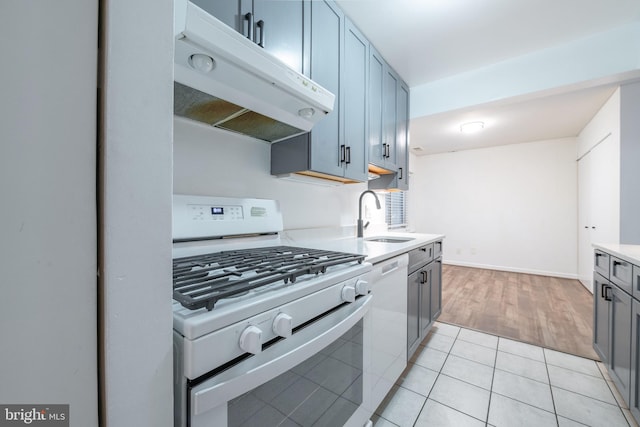 kitchen with gray cabinets, white appliances, sink, and light hardwood / wood-style flooring