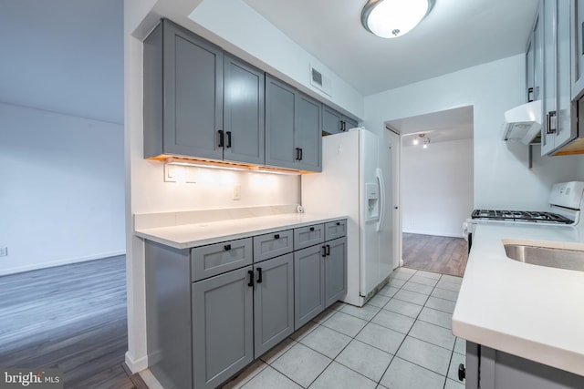 kitchen featuring white appliances, ventilation hood, light hardwood / wood-style flooring, and gray cabinets