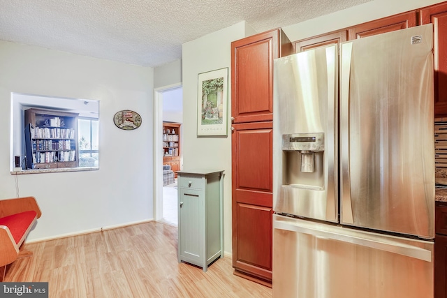 kitchen featuring a textured ceiling, stainless steel refrigerator with ice dispenser, and light wood-type flooring