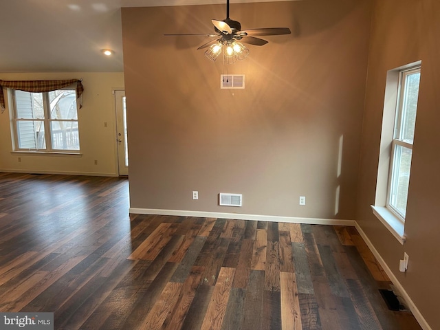 unfurnished room featuring a healthy amount of sunlight, dark hardwood / wood-style flooring, and ceiling fan