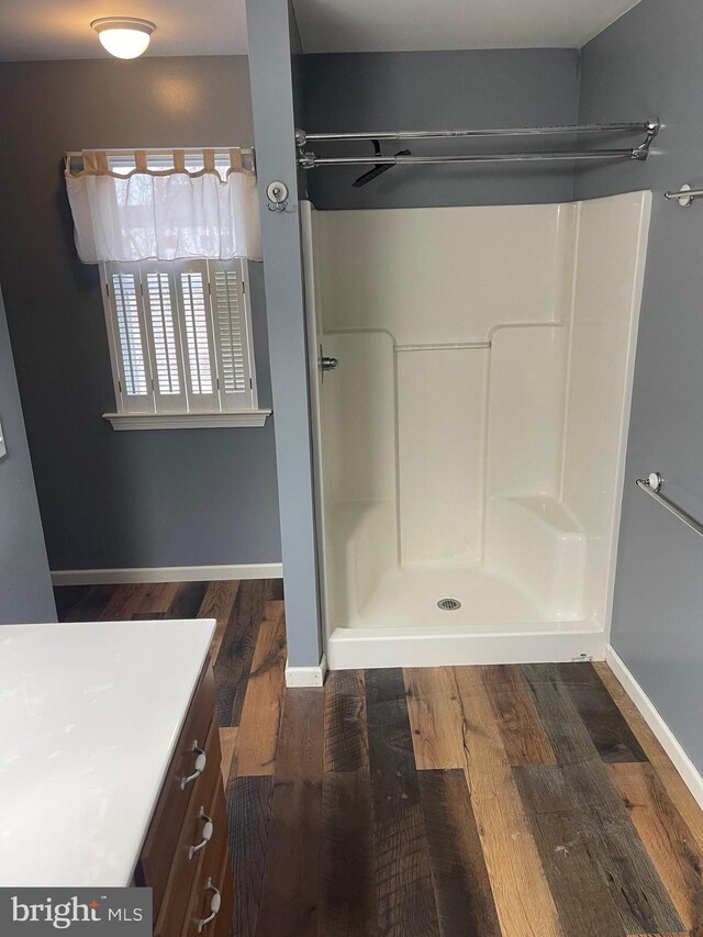 bathroom featuring vanity, wood-type flooring, and walk in shower