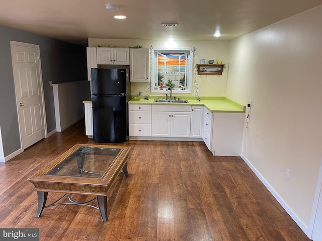 kitchen with dark hardwood / wood-style flooring, sink, black fridge, and white cabinetry