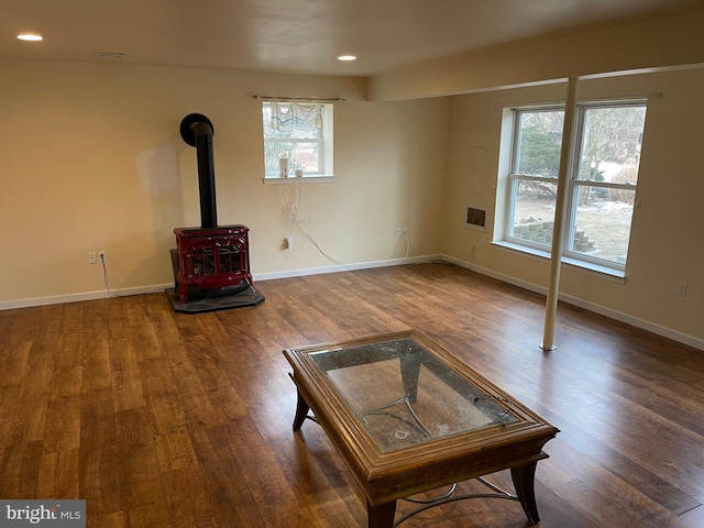 unfurnished living room featuring dark hardwood / wood-style floors, a wealth of natural light, and a wood stove