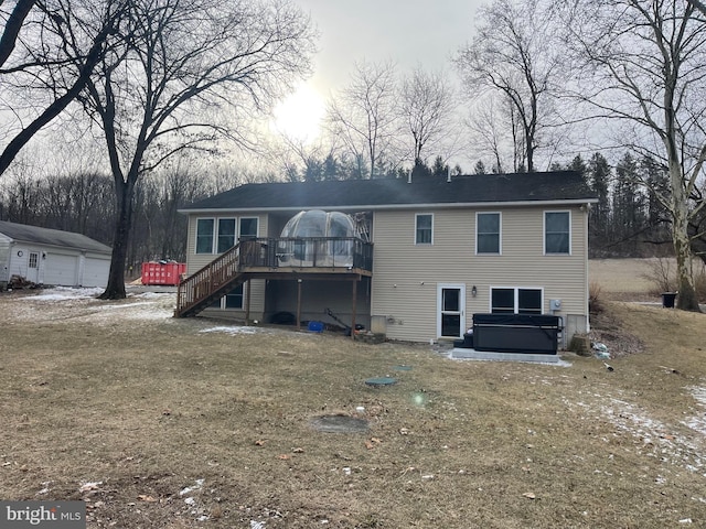 back of property featuring a garage, an outbuilding, a yard, a hot tub, and a deck