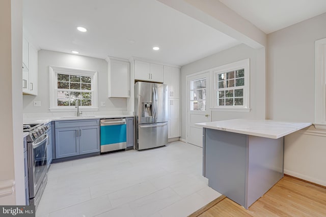 kitchen with kitchen peninsula, appliances with stainless steel finishes, sink, light hardwood / wood-style flooring, and white cabinetry