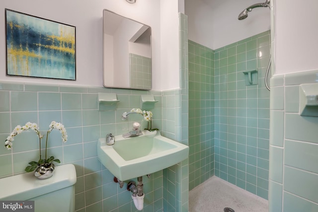 bathroom with toilet, tile walls, and tiled shower