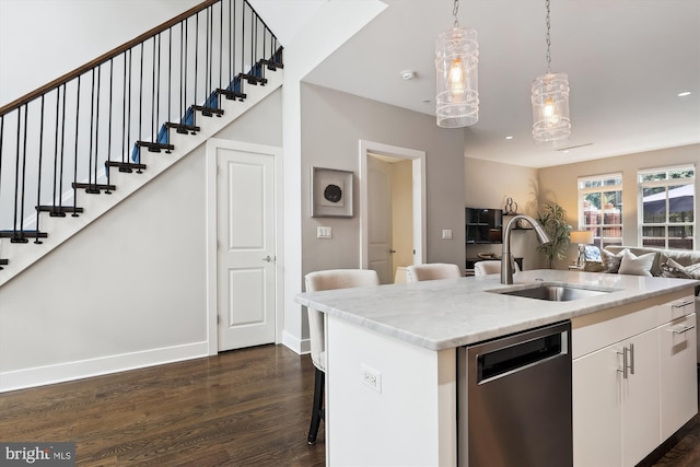 kitchen featuring white cabinets, dishwasher, an island with sink, sink, and hanging light fixtures