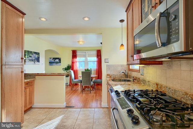 kitchen with light stone countertops, sink, pendant lighting, light tile patterned floors, and appliances with stainless steel finishes