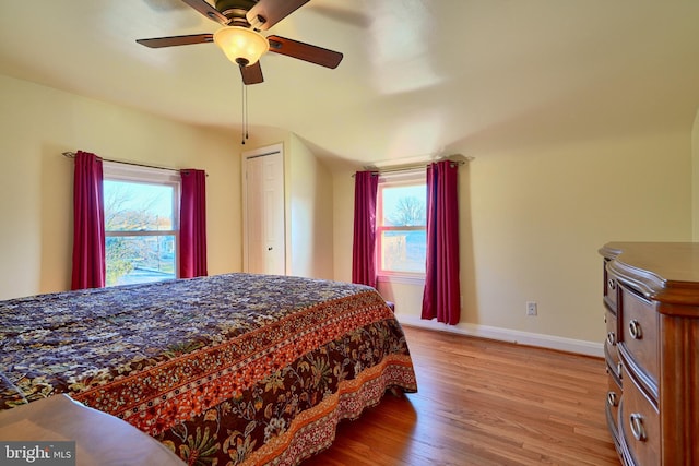 bedroom with ceiling fan, a closet, multiple windows, and light hardwood / wood-style flooring