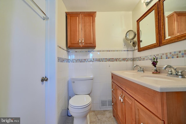 bathroom with tile patterned floors, vanity, toilet, and tile walls