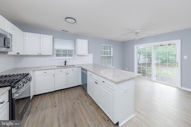 kitchen with kitchen peninsula, stainless steel appliances, and white cabinets