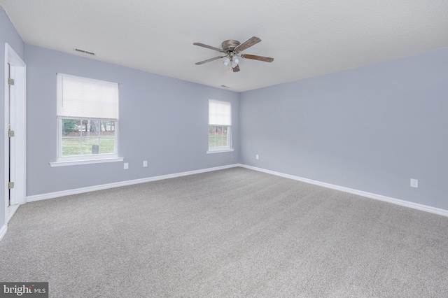 carpeted spare room with plenty of natural light, ceiling fan, and a textured ceiling