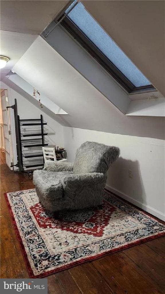 living area with vaulted ceiling with skylight and wood-type flooring