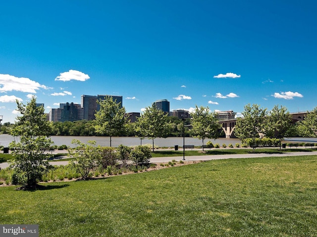 view of property's community with a view of city, a yard, and a water view