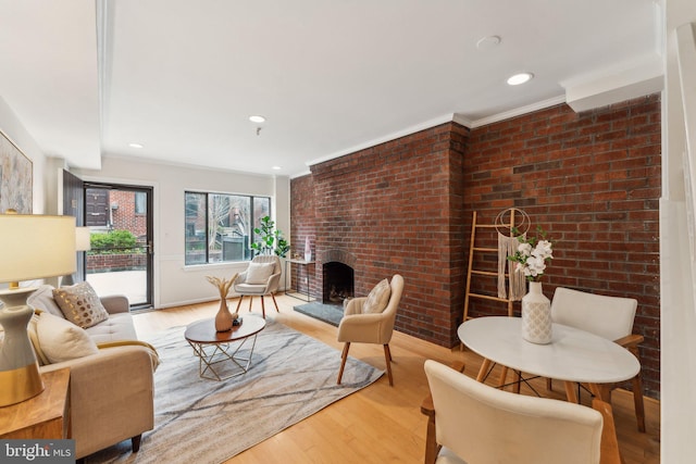 living room with a fireplace, crown molding, wood finished floors, and brick wall