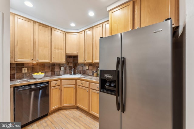 kitchen featuring tile countertops, backsplash, appliances with stainless steel finishes, and a sink