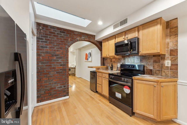 kitchen featuring visible vents, appliances with stainless steel finishes, a skylight, decorative backsplash, and tile counters