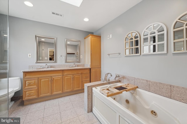 bathroom featuring tile patterned floors, vanity, toilet, and a tub to relax in